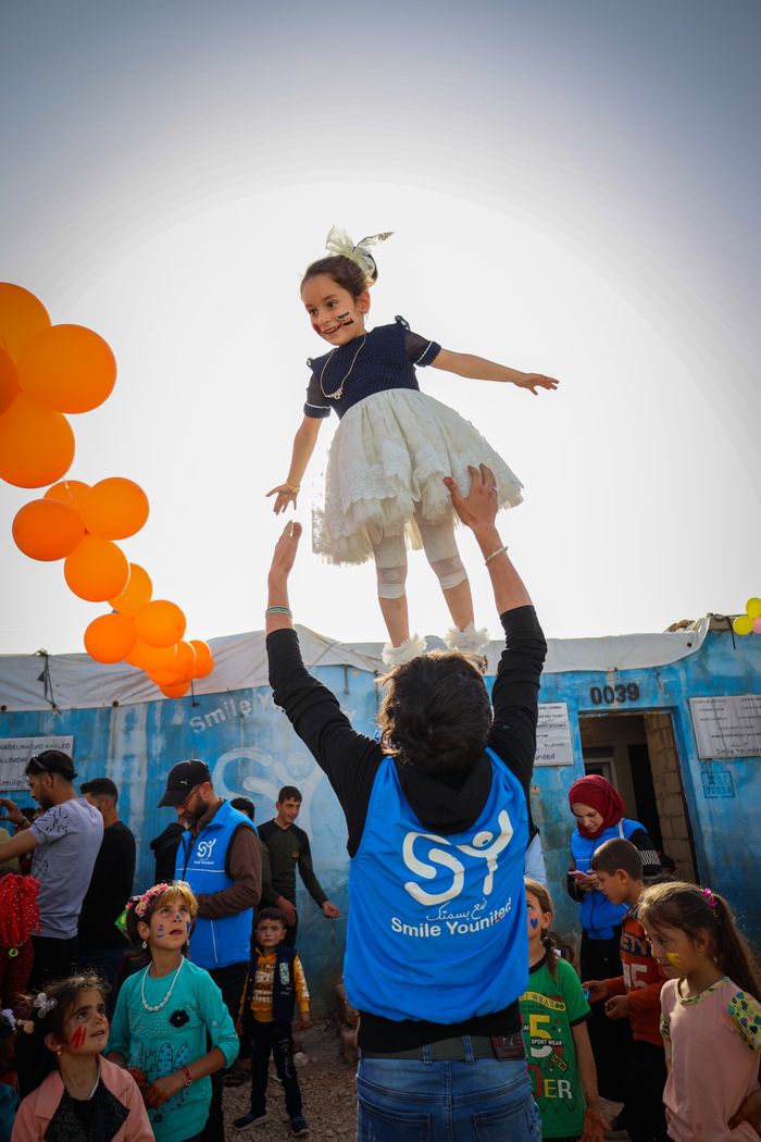 why-choose-us Children enjoying fun activities outdoors in Idlib, Syria, with balloons and festive atmosphere.