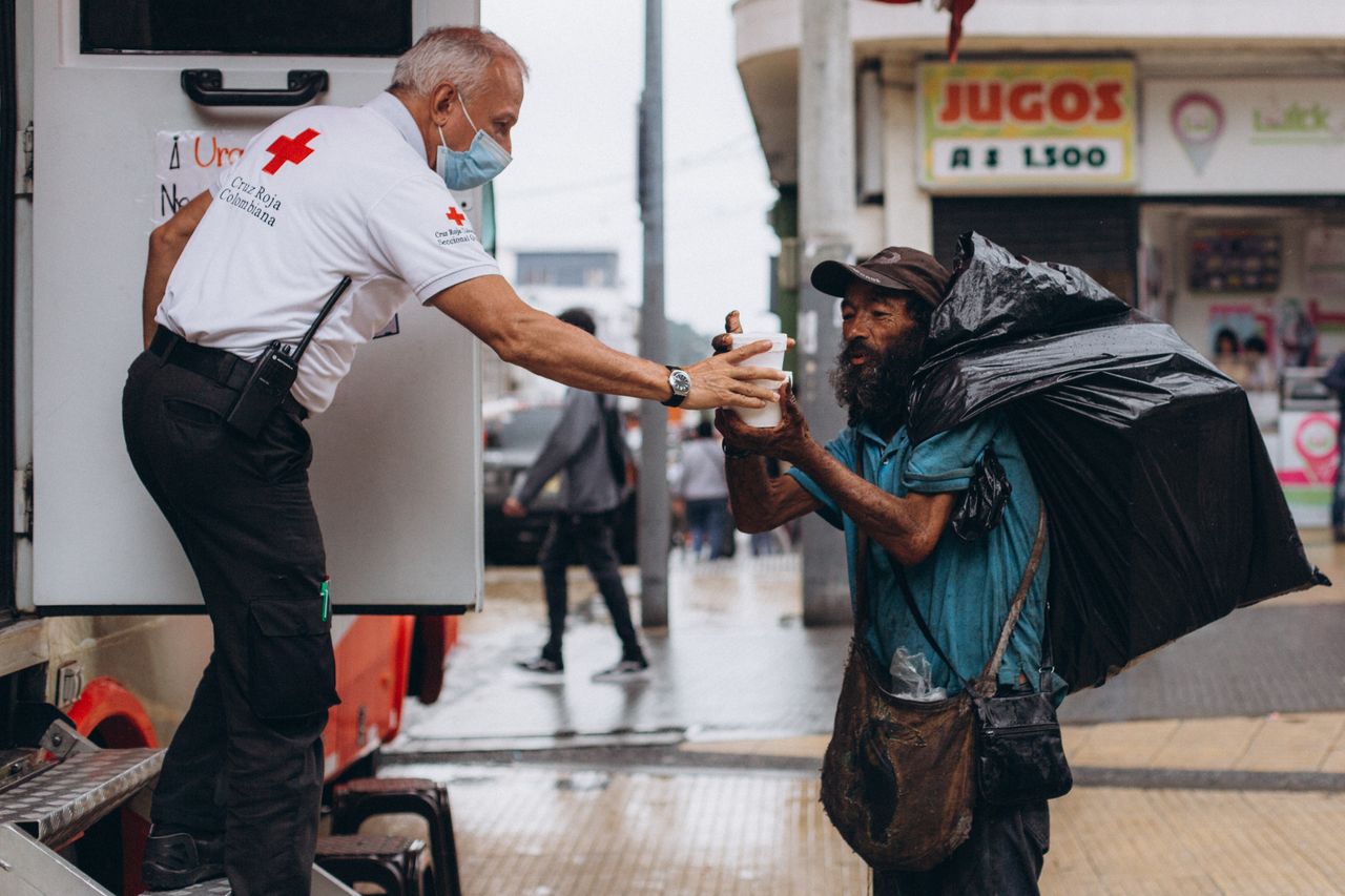 about-01 Red Cross worker assisting a homeless man outdoors with kindness.